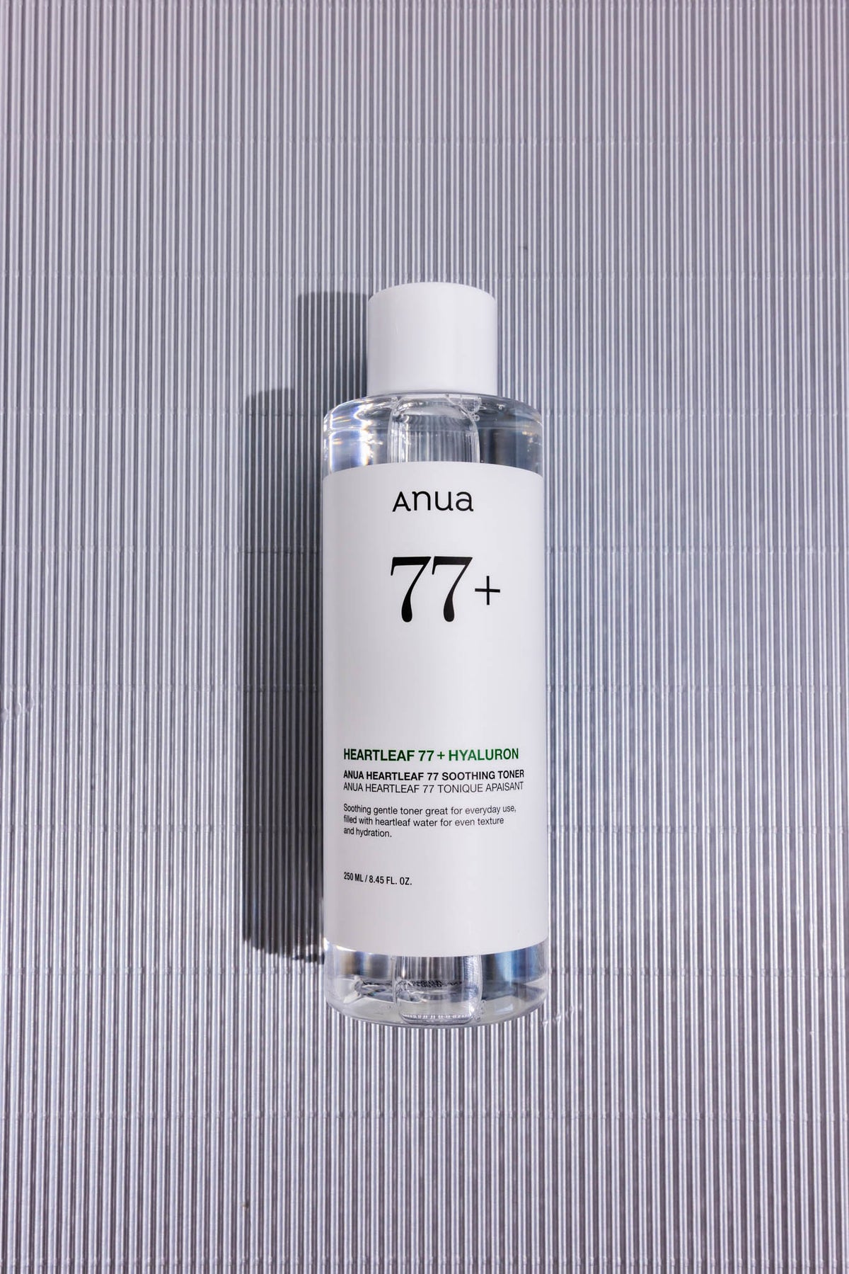 Lotion tonique apaisante Heartleaf 77 % Anua, flacon posé sur fond strié gris, vue de dessus