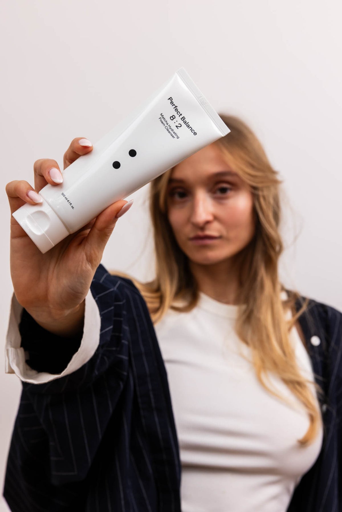 Mousse nettoyante hydratante au matcha B:lab, mannequin tendant un tube blanc vers l’objectif