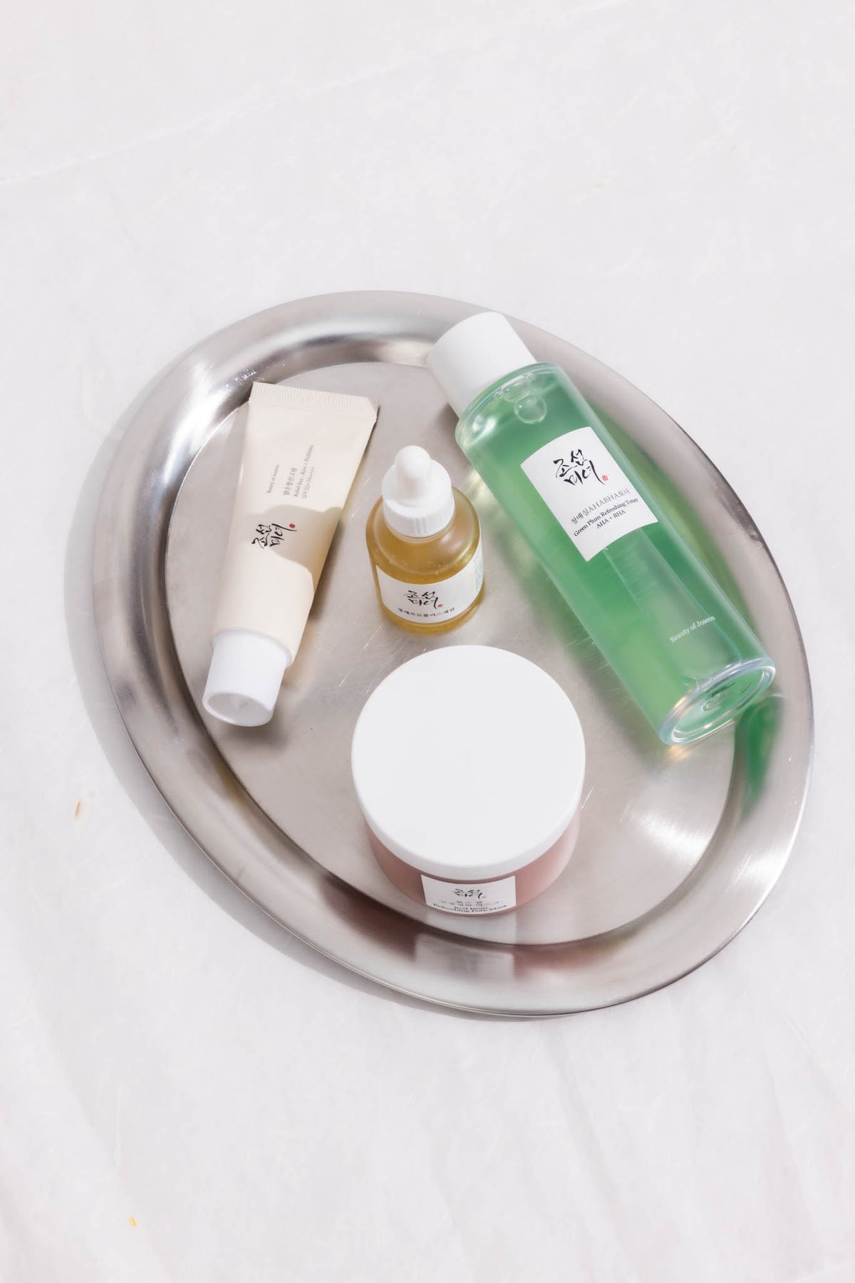 Crème solaire Relief Sun Rice + Probiotics Beauty of Joseon, tube sur un plateau métal avec trois autres soins de la marque