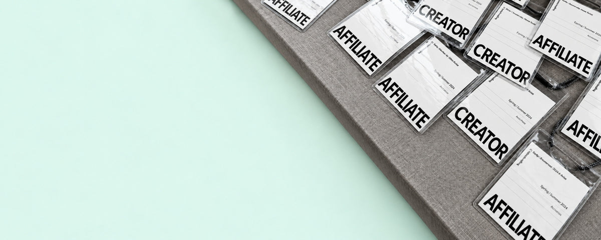Badges Creator et Affiliate posés sur un tapis gris, fond menthe