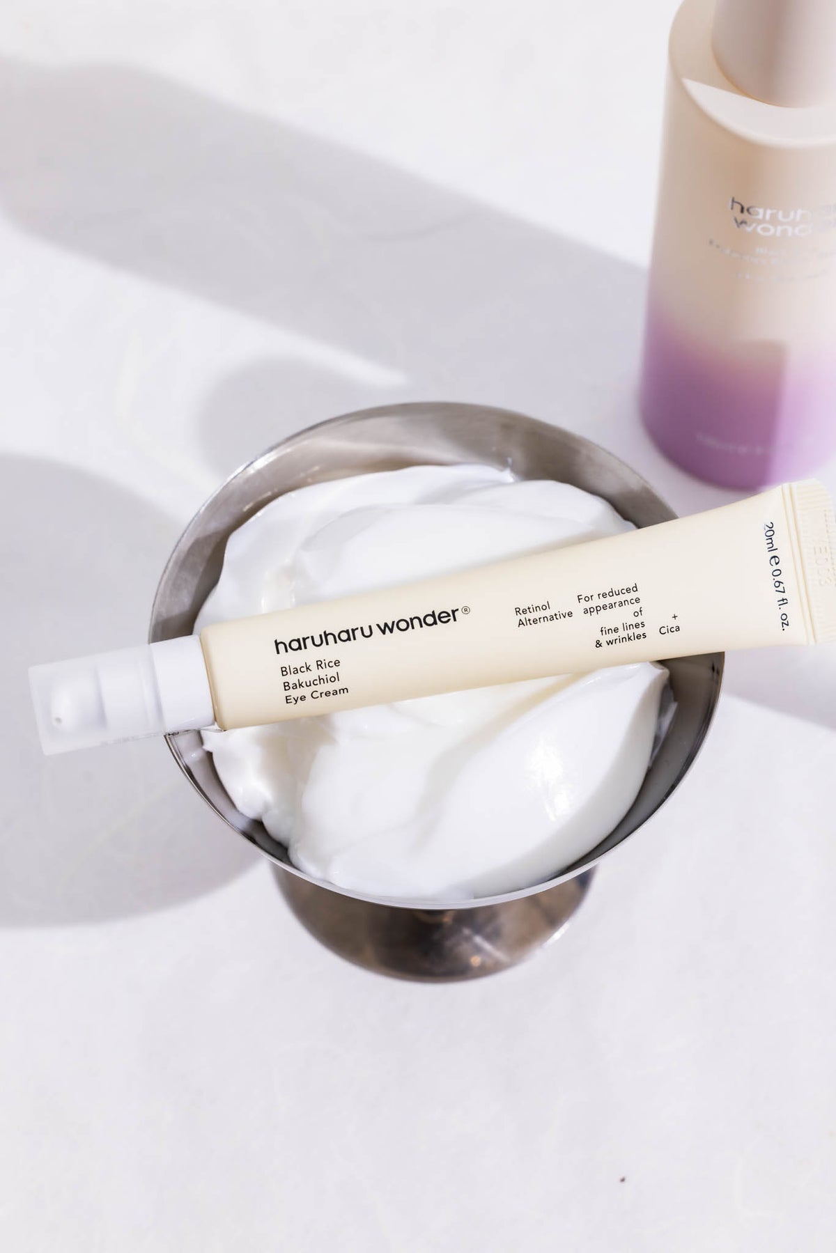 Crème yeux Black Rice Bakuchiol Haruharu Wonder, tube posé sur une coupe remplie de crème