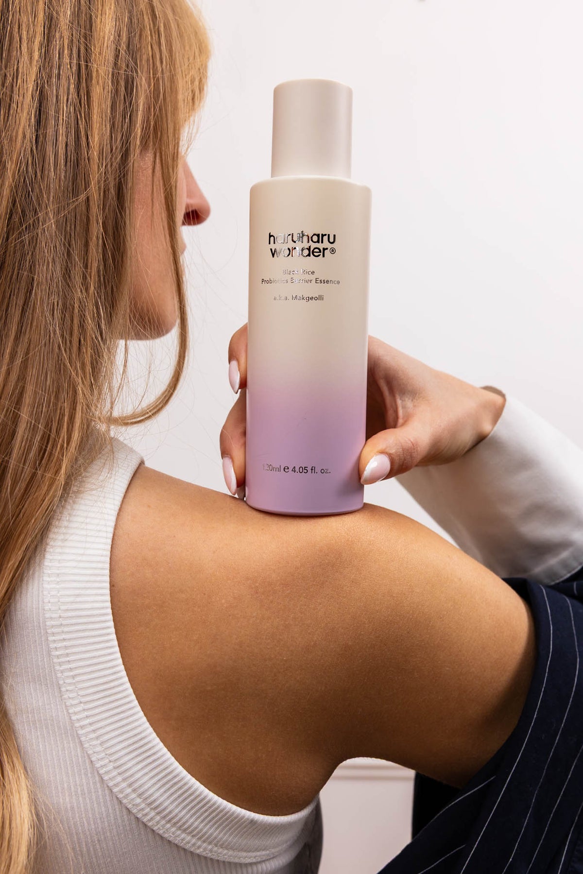 Essence Black Rice Probiotics Barrier Haruharu Wonder, mannequin tenant le flacon sur l’épaule