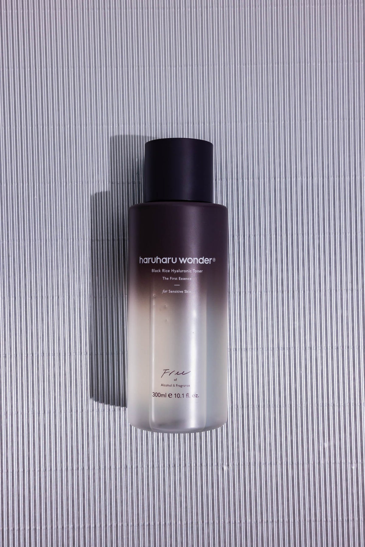 Lotion tonique au riz noir et acide hyaluronique Haruharu Wonder, flacon de 300 ml posé sur fond strié gris