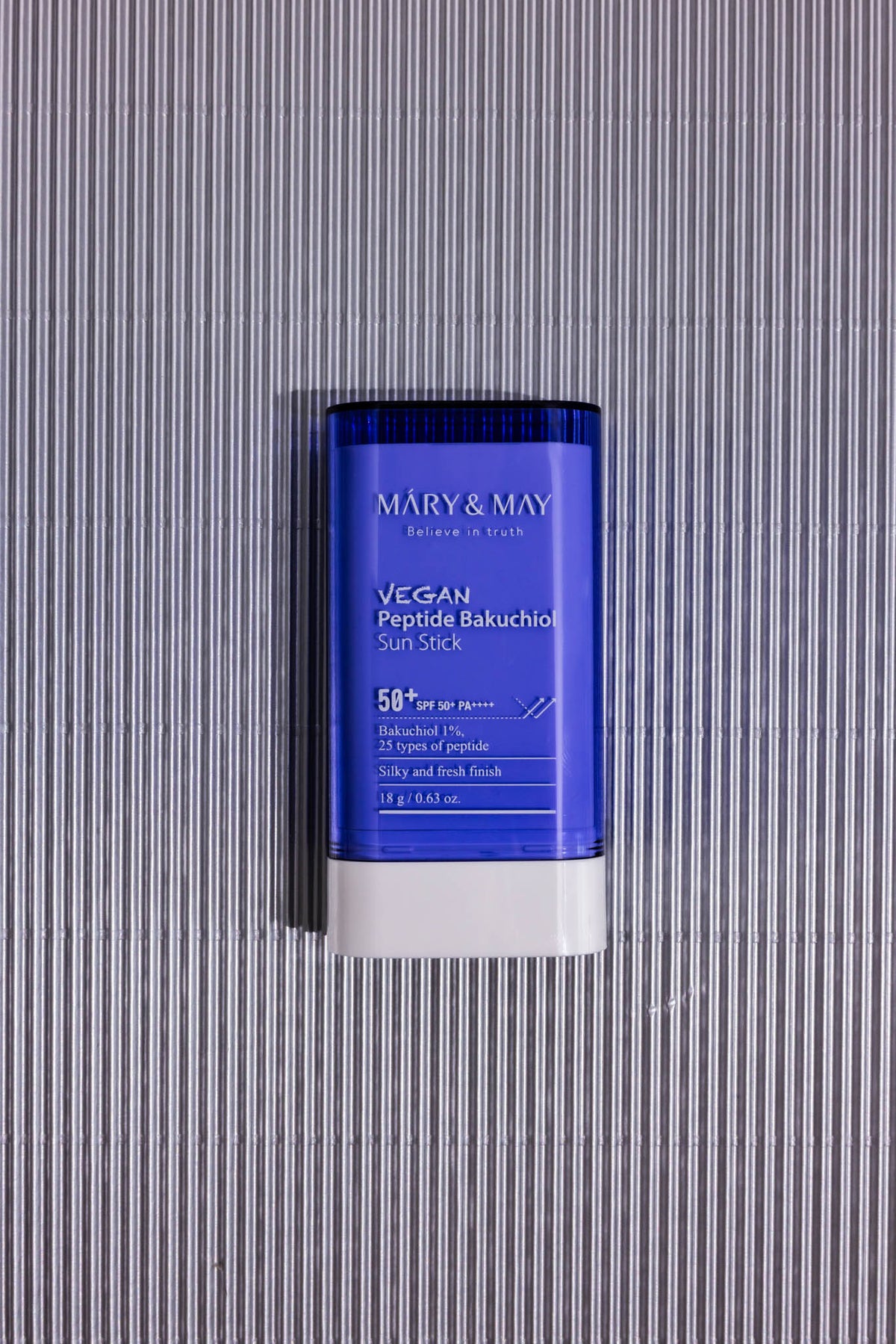 Stick solaire Vegan Peptide Bakuchiol SPF50+ PA++++ Mary & May, stick bleu sur fond gris strié