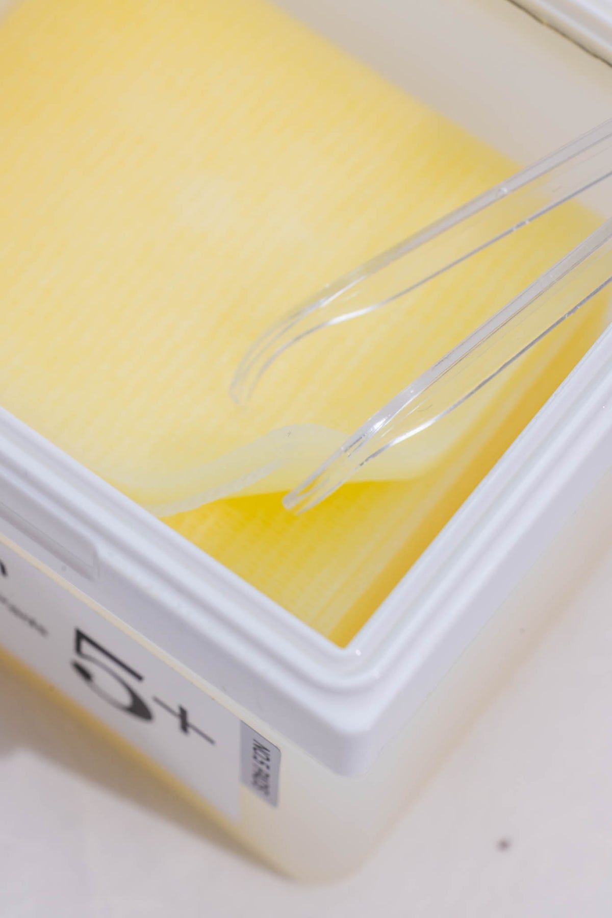 Disques No.5+ Glutathione Vitamin-Niacinamide Numbuzin, pot ouvert, disques jaunes saisis à la pince
