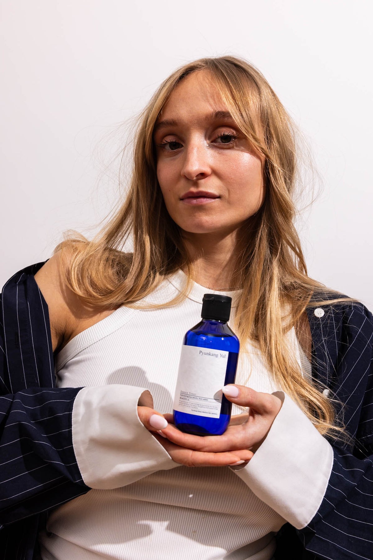 Lotion tonique Essence Toner Pyunkang Yul, mannequin tenant le flacon à deux mains
