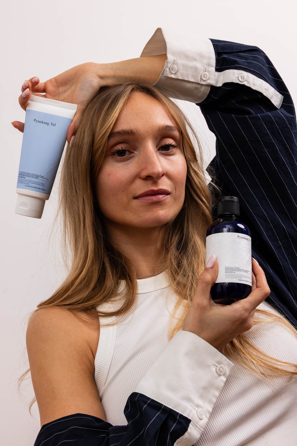 Mousse nettoyante purifiante Low pH Pyunkang Yul, mannequin tenant le tube et un flacon de la marque