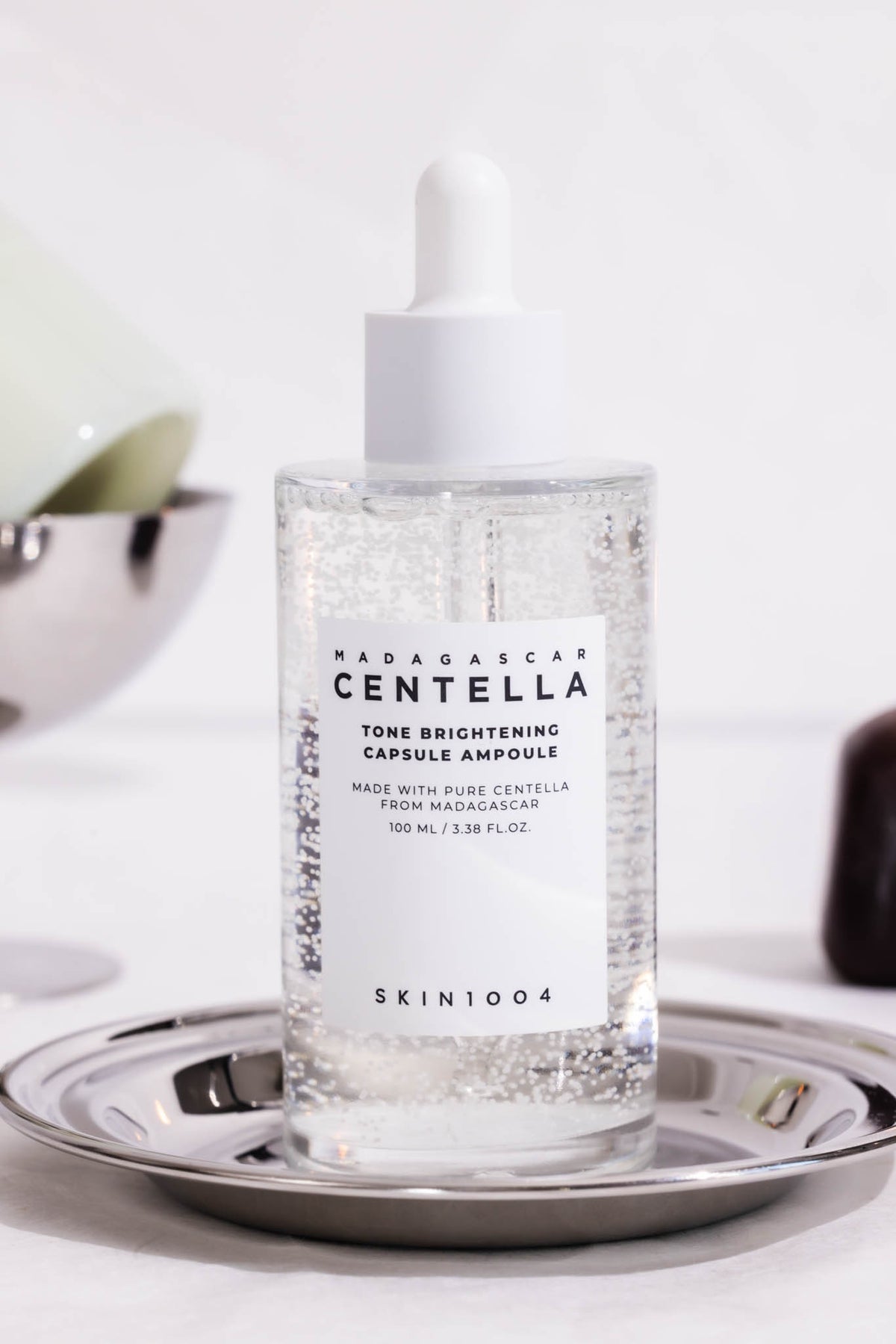 Ampoule Madagascar Centella Tone Brightening Capsule SKIN1004, flacon compte-gouttes sur une coupelle en métal