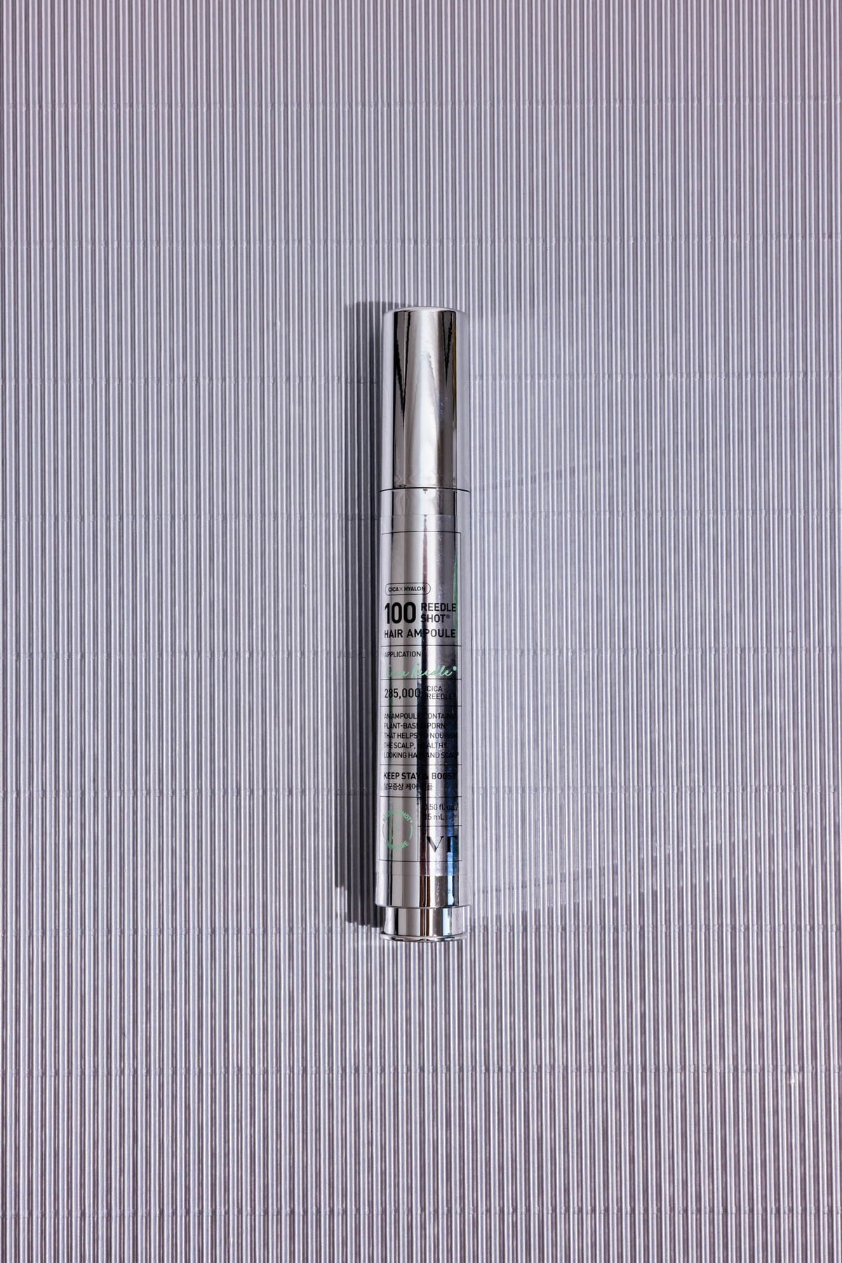 Ampoule cheveux PDRN Reedle Shot Hair 100DL VT, flacon argenté posé sur fond strié gris, vue de dessus