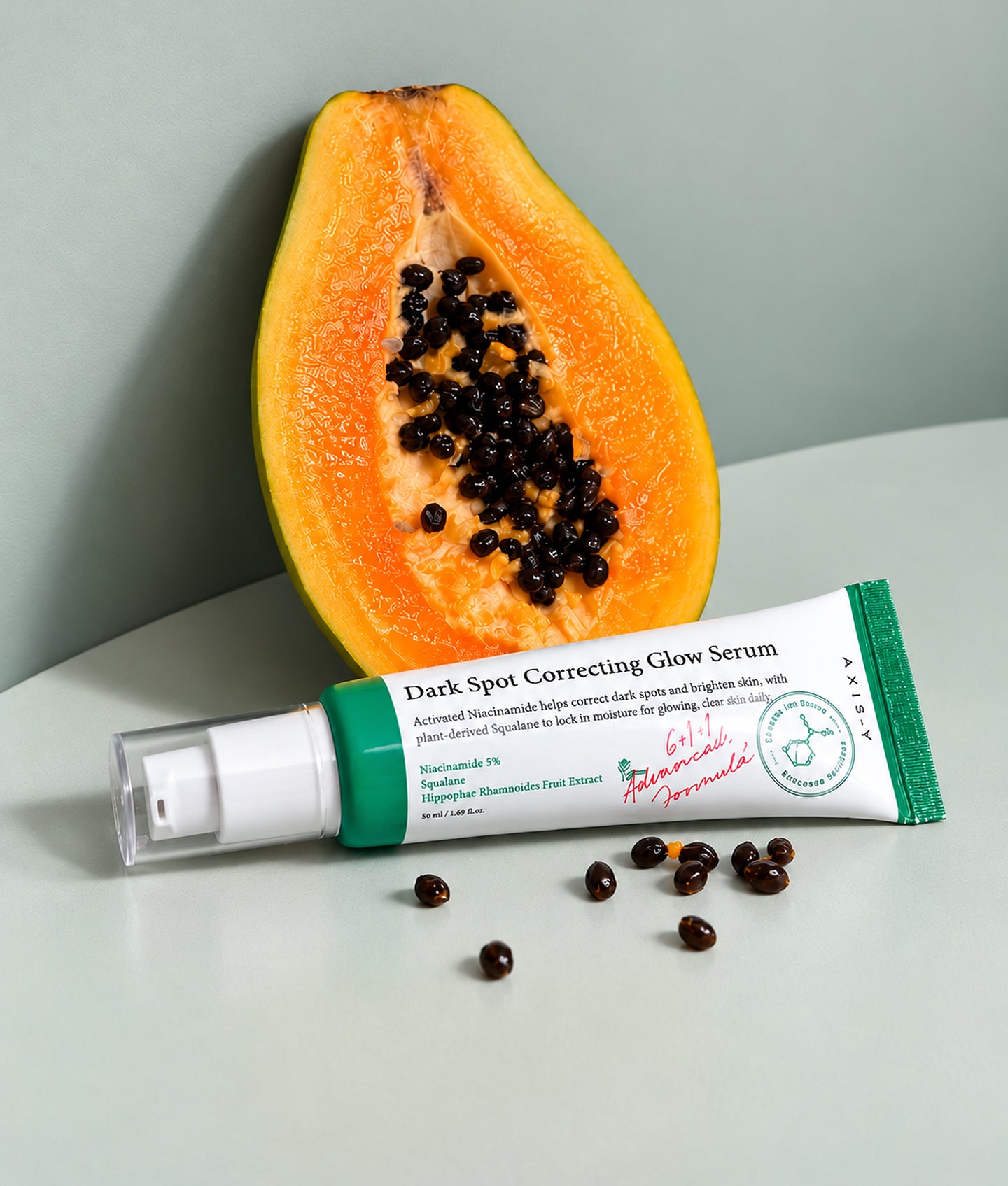 AXIS-Y, tube Dark Spot Correcting Glow Serum devant une demi-papaye et ses graines
