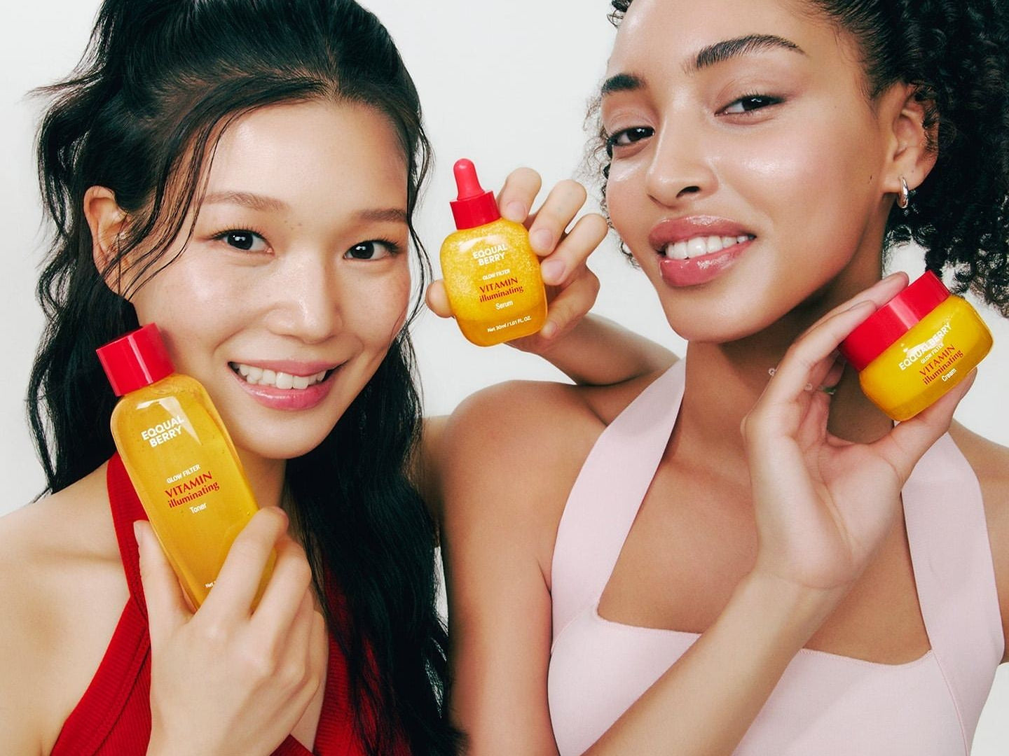 Eqqualberry, deux jeunes femmes souriantes présentent des flacons orange de la gamme vitamine