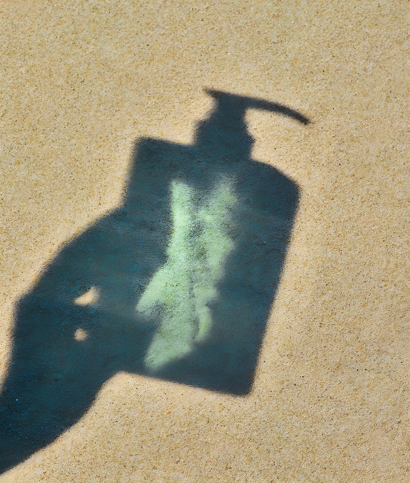 GROWUS, ombre d’un flacon pompe projetée sur du sable
