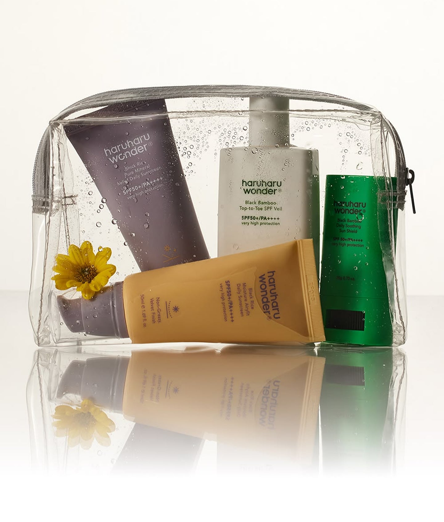 Haruharu Wonder, trousse transparente remplie de tubes et flacons de la marque, avec une fleur jaune