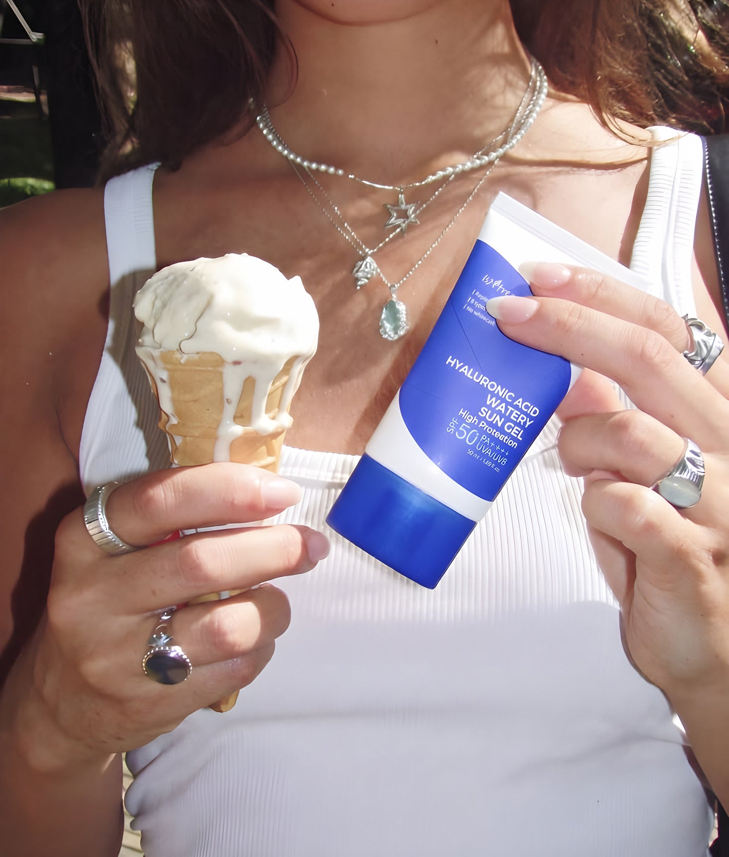 Isntree, jeune femme tenant un cornet de glace et un tube bleu de soin solaire à l’acide hyaluronique