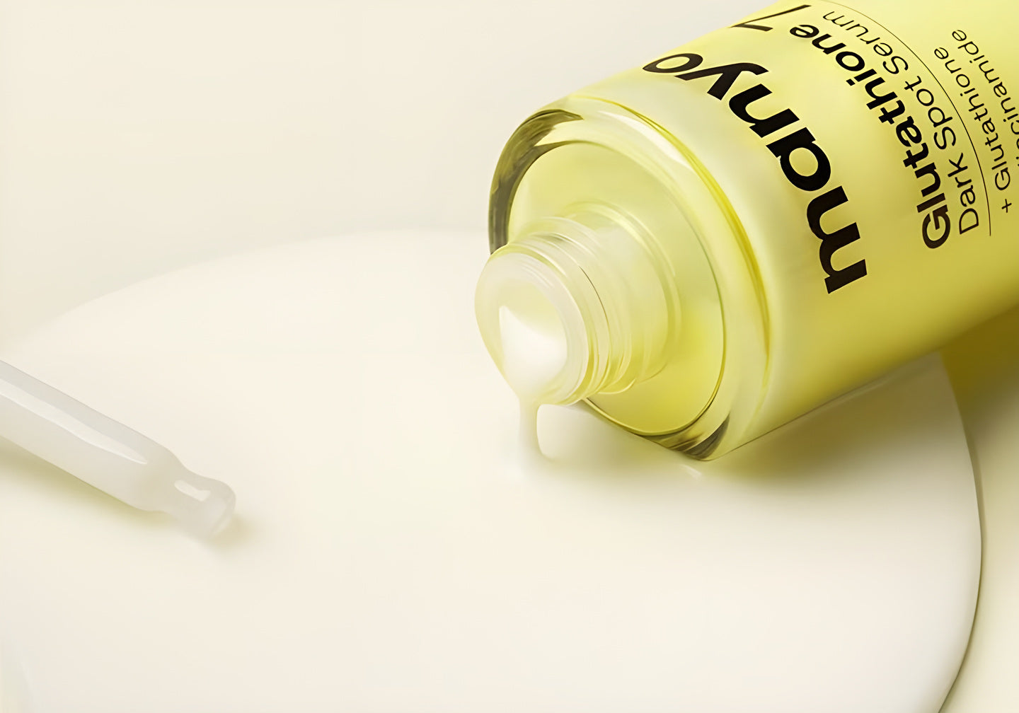 Manyo, flacon jaune Glutathione Dark Spot Serum couché dans une flaque de texture laiteuse