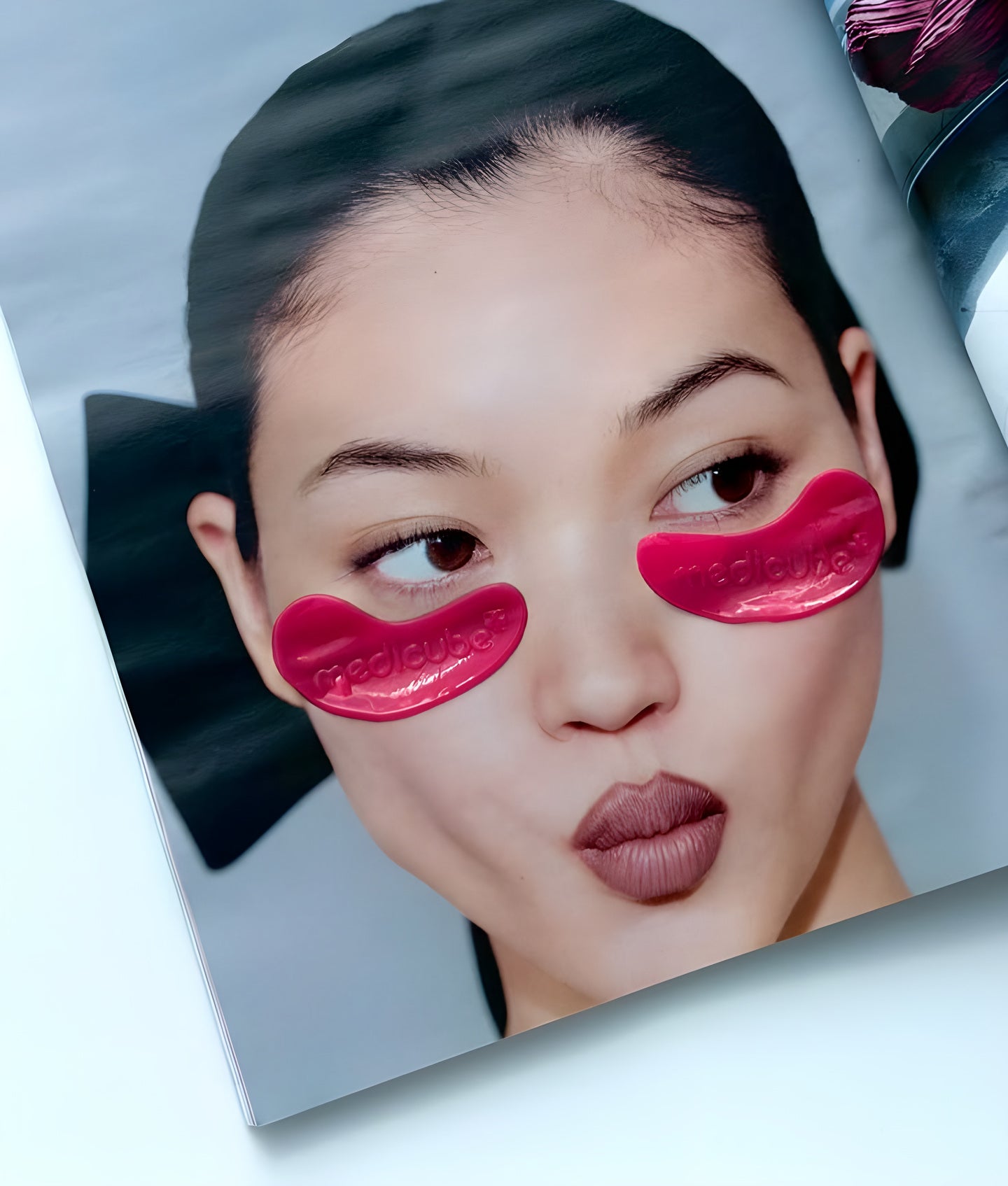 Medicube, visage de femme imprimé, des patchs rouges sous les yeux