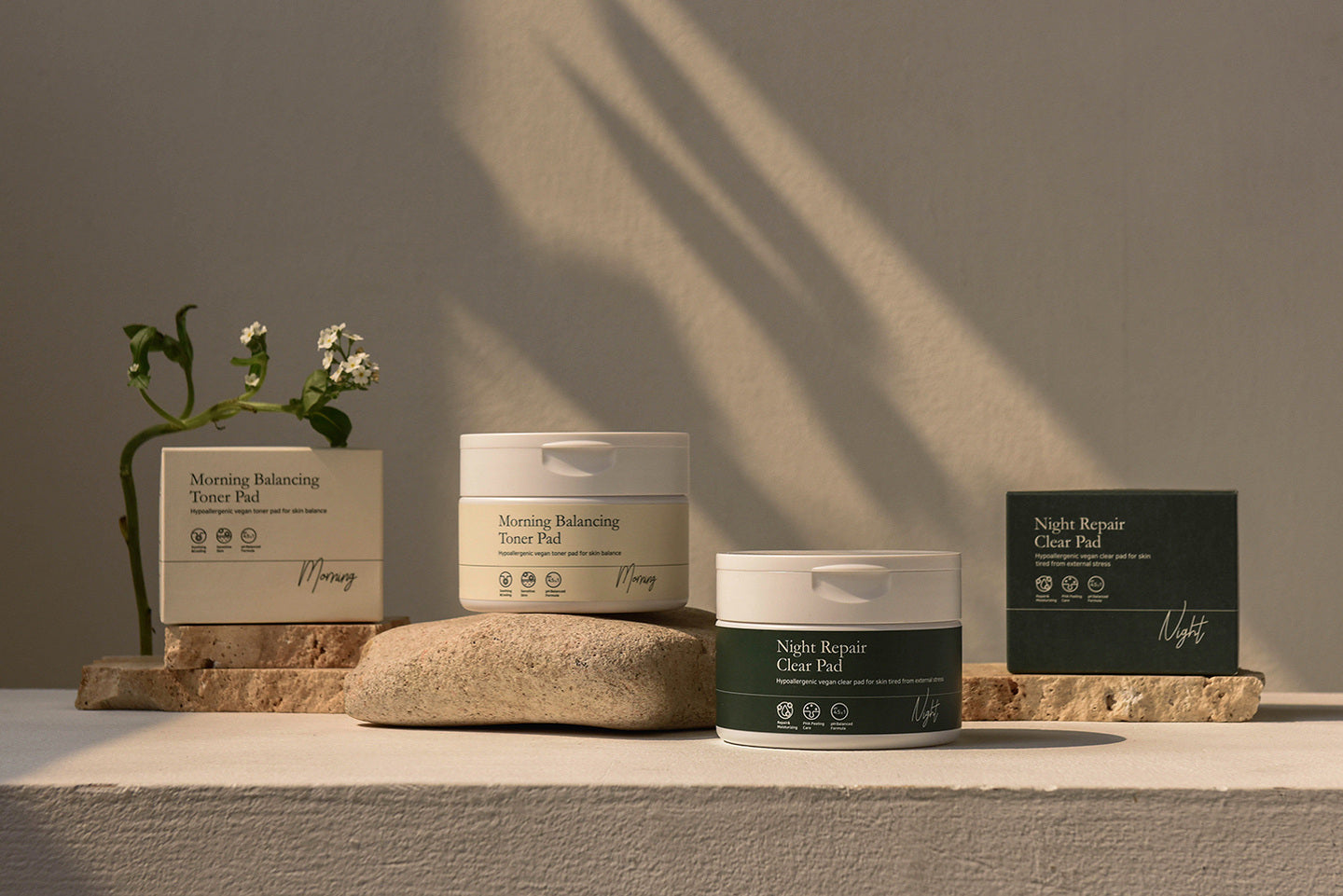 NOAV, pots et boîtes Morning Balancing Toner Pad et Night Repair Clear Pad sur une pierre